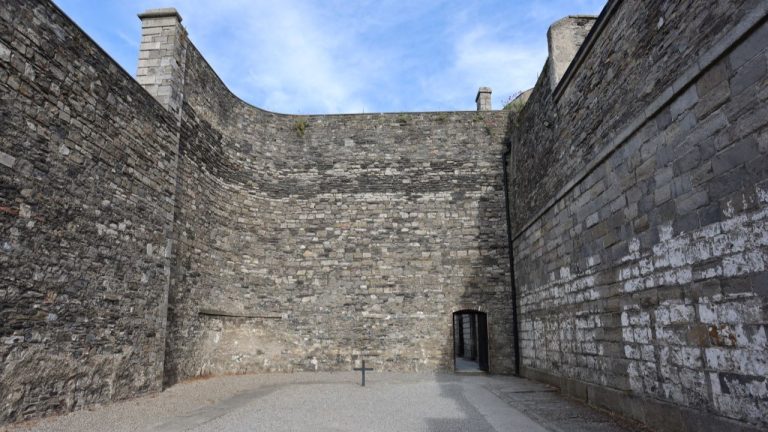 cour ceinturée de hauts murs au fond de laquelle se trouve une croix